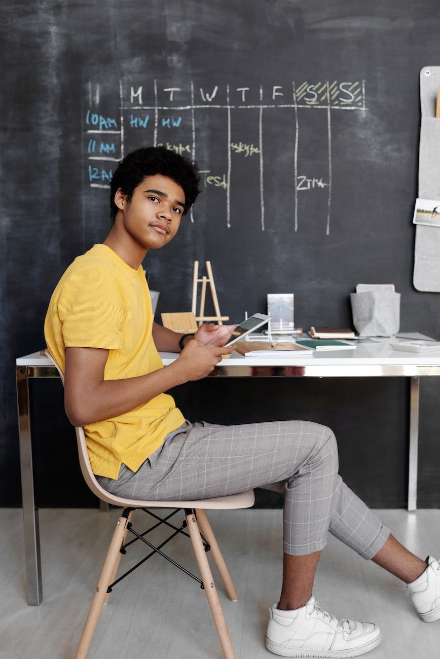 photo of boy sitting on chair while holding an ipad